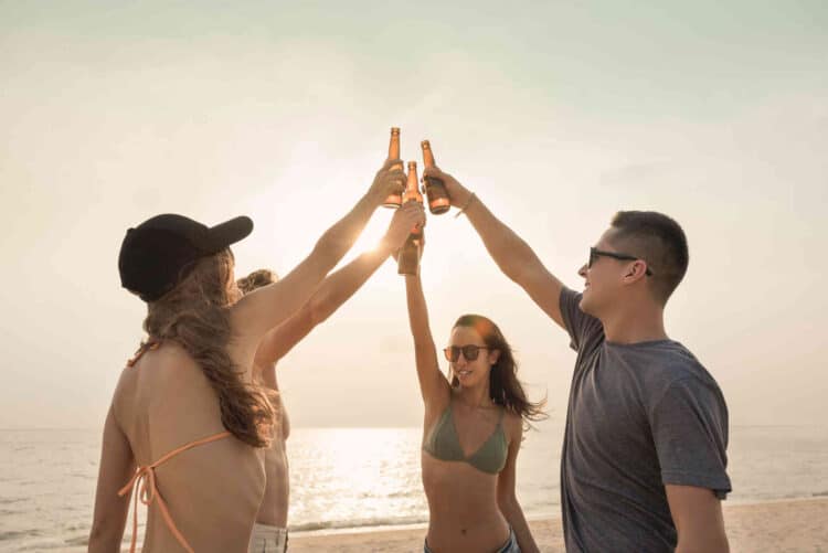 Bierabsatz in Deutschland gestiegen. Gruppe feiert am Strand mit Bier.