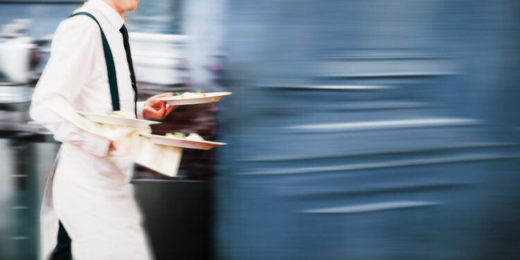 Kellner mit Tellern eilig auf dem Weg zum Gast