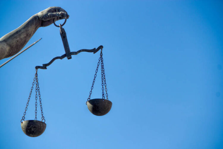 Arm einer Justizia-Statue mit Waagschalen