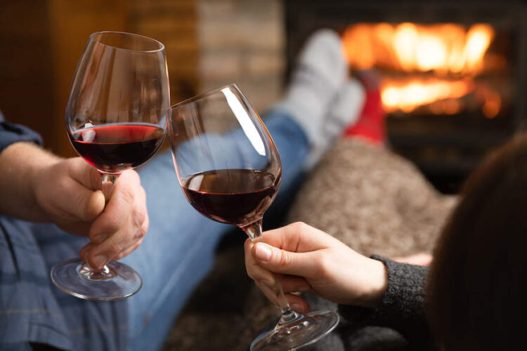 Paar mit Rotwein vor dem Kamin