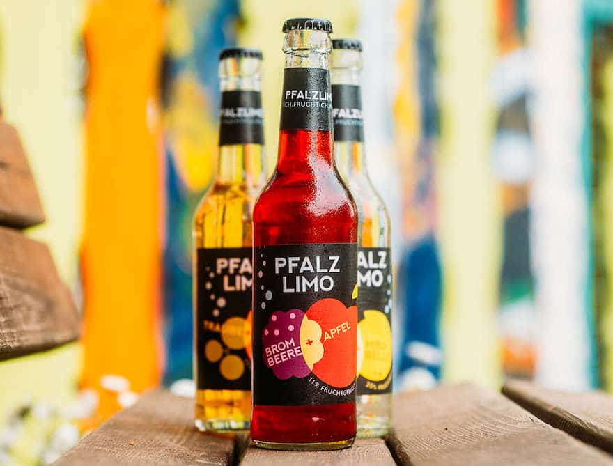 Drei Flaschen Pfalzlimo auf einer Parkbank stehend