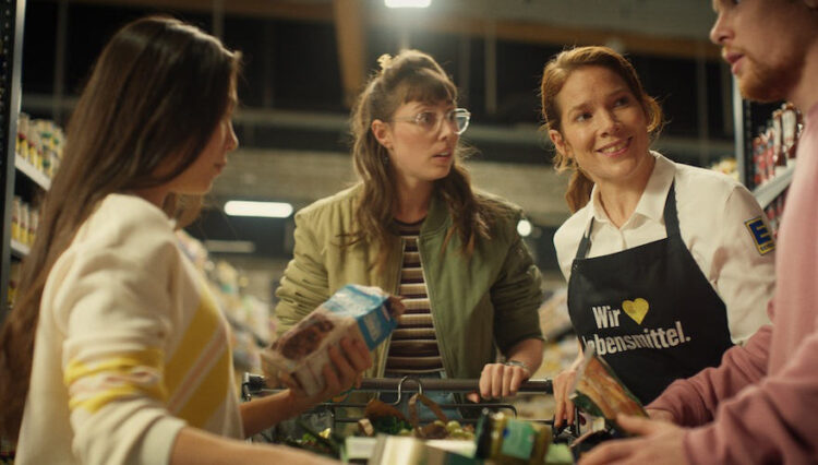 Ausschnitt aus der neuen Edeka-Kampagne/junge Kunden mit Edeka-Verkäuferin