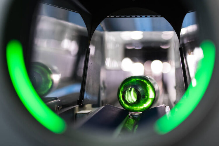 Grüne PET-Flasche im Schacht eines Leergutautomaten