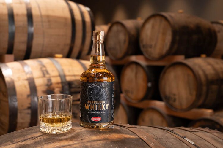 Foto der Flasche und ein eingeschenktes Glas vor Holzfässern