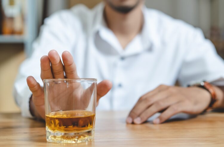 Mann schiebt ein Whiskyglas von sich weg.