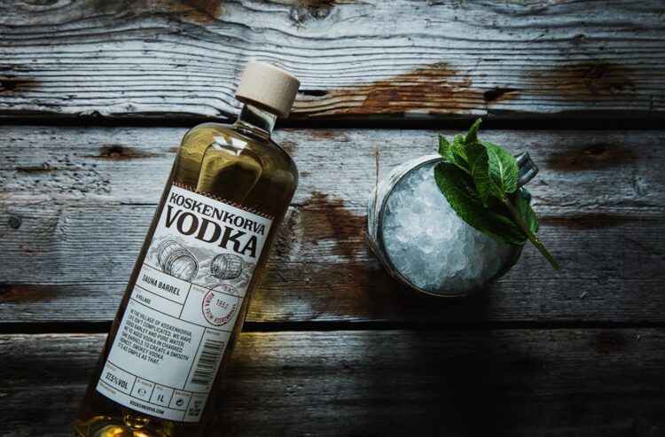 Koskenkorva-Flasche und Longdrink-Glas auf alten Holzbohlen