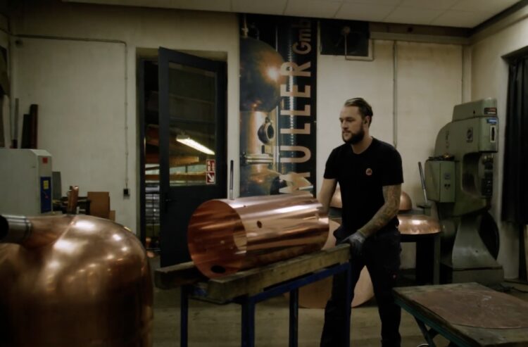 Handwerker baut aus einem Kupferblech eine Brennblase.