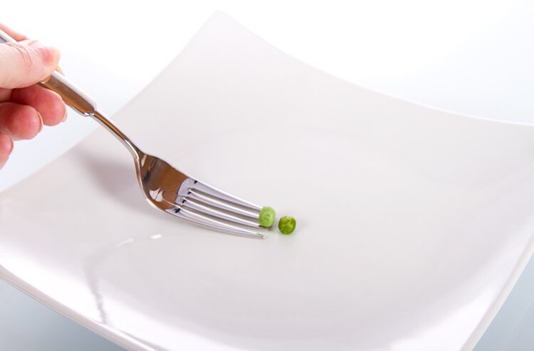 Gabel auf weißem Teller mit zwei Erbsen