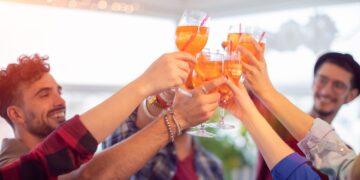 Junge Leute feiern und stpßen mit Aperol Spritz an.