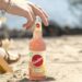 Frau am Strand mit einer Flasche Sinalco Leichte Limo in der Longneckflasche