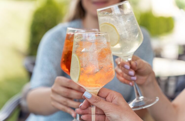 Frau stoßen mit bunten Aperitifs an