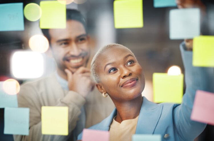 Zwei junge Leute vor einer Glaswand mit bunten Haftnotizen