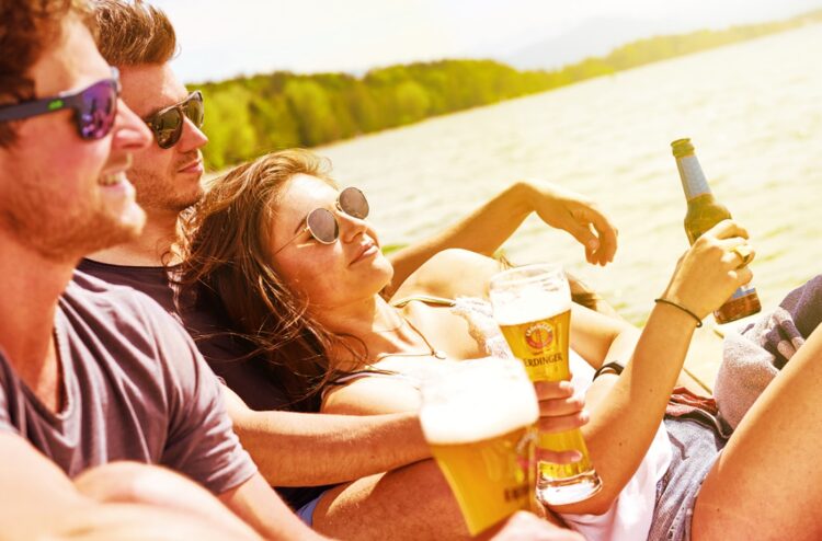 Foto von jungen Leuten, die in der Abendsonne Erdinger trinken.