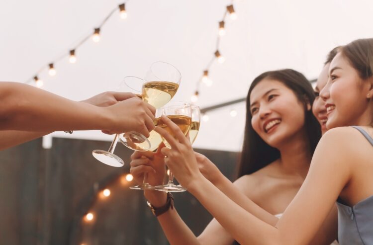 Asiatische Frauen stoßen mit Weißwein an.