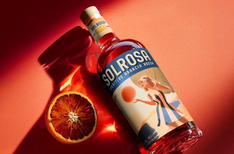 eine liegende Flasche Solrosa mit einer Blutorange