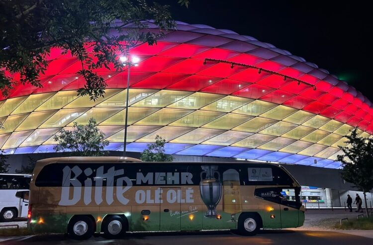 Bus mit Bitburger-Schriftzug vor beleuchtetem EM-Stadion