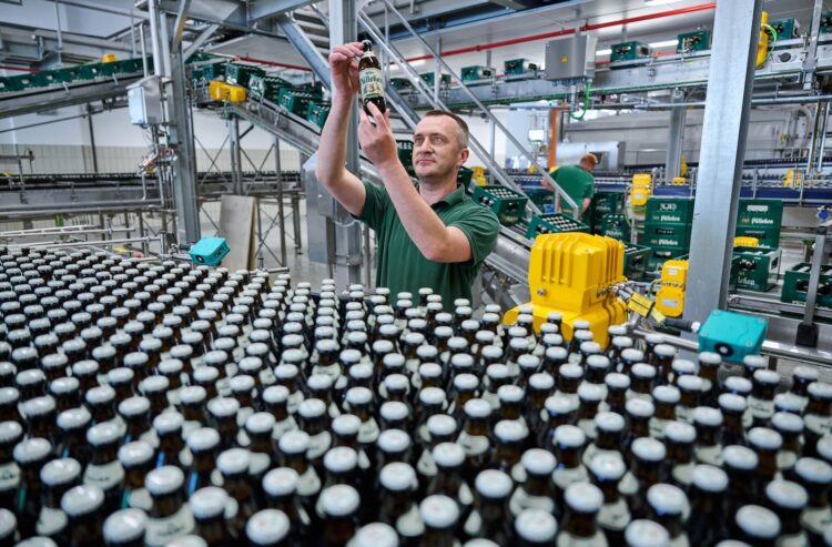 Mann in der Produktion prüft eine Flasche Pülleken