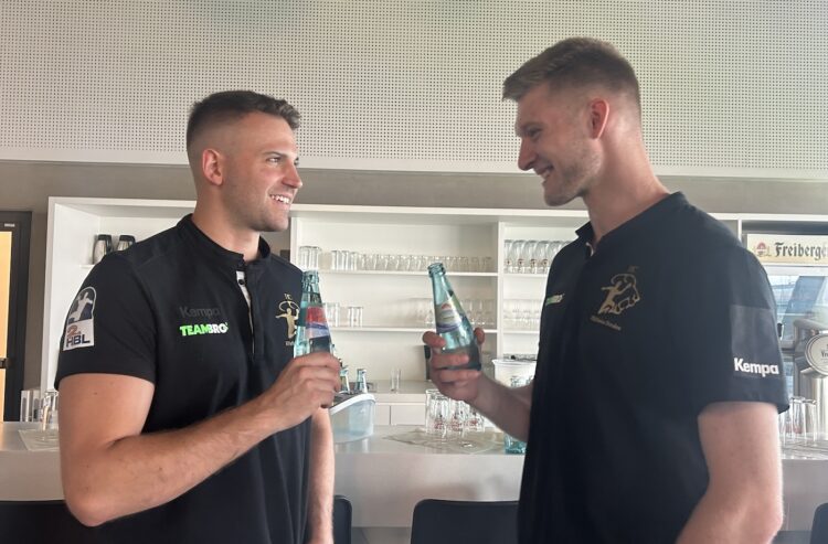 Zwei Sportler stoßen mit Mineralwasserflaschen an.