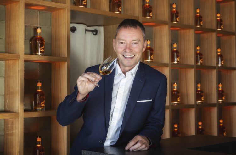 Helmut Knöpfle vor einem dekorativen Whiskyregal