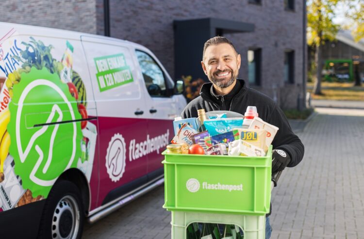 Flaschenpost-Fahrer mit Lebensmittel- und Getränkekisten vor seinem Lieferfahrzeug
