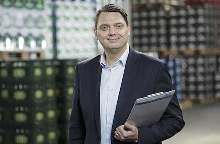 Geschäftsführer Tobias Gröger stehend vor Getränkekisten