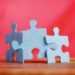 Drei Puzzleteile auf einem Tisch vor rotem Hintergrund