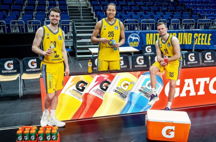 Drei Basketballspieler an einer Bandenwerbung von Gatorade