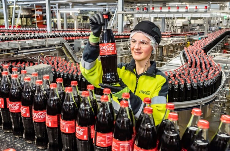 Mitarbeiterin an einer Glas-Linie von Coca-Cola