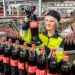 Mitarbeiterin an einer Glas-Linie von Coca-Cola