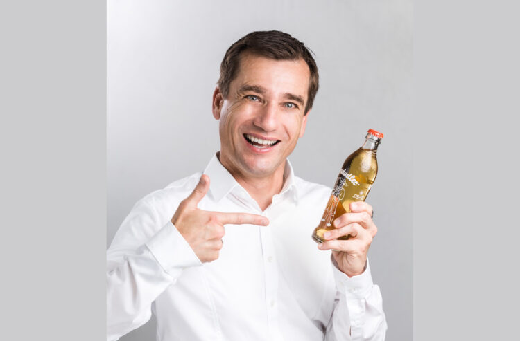 Porträt Mike Mühlberger mit Almdudler-Flasche